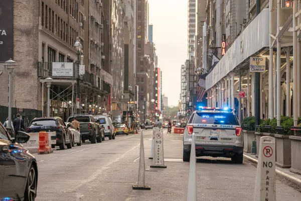 New York City, New York, ABD - 07.29.2024: Bir NYPD polis aracı, Manhattan 'da arabalarla ve iskelelerle kaplı bir sokakta ışıkları yanıp sönüyor. Şehir manzarası şehir yaşamını, akşam ışığını ve New York 'taki kolluk kuvvetlerinin varlığını yansıtıyor.