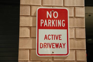 Tuğla duvarda asılı olan açık hava tabelası uyarıcıdır. Metinde, bölgede kurallara uymanın önemini vurgulayan, 