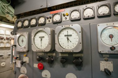Bir denizaltı motor kontrol panelinde geniş analog kadranlar, RPM göstergeleri ve döner düğmeler bulunur. Panel hız ve yön yönetimi için kullanılan karmaşık bir sistemin parçasıdır..