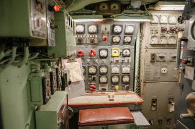 Antika bir denizaltı kontrol bankı analog ölçerler, anahtarlar ve kırmızı valf kollarıyla çevrilidir. Paneller ve göstergeler güç, basınç ve motor durumunu izlemek için kullanılır.