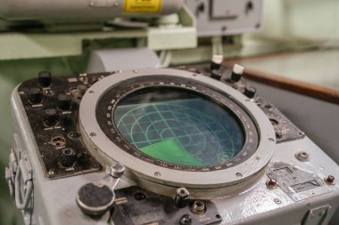 Dairesel yeşil ekran ve mekanik kontrollü eski donanma radar konsolu. Radar, denizdeki nesneleri tespit etmek için kullanılan bir tarama ızgarası gösteriyor..