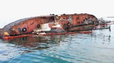 Old rusty oil tanker on its edge in the shallow water. Sunken drowned ship after the shipwreck.