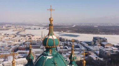 Ortodoks Kilisesi 'nin altın kubbeleri ve şehir binaları ve nehir üzerindeki yeşil çatısı kış günlerinde. Arka planda gökyüzü.
