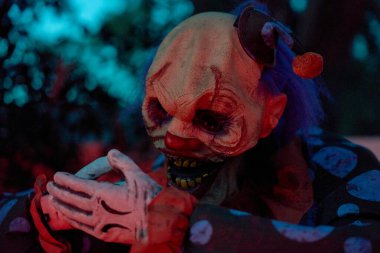 Çarpık katmanlar, mavi ve kırmızı ışıktaki tüyler ürpertici bir palyaçonun gerçek üstü bir portresini oluşturuyor. Sanatsal bokeh, hareket çizgileri ve kopya çerçeveler ürkütücü Cadılar Bayramı stili ekler.