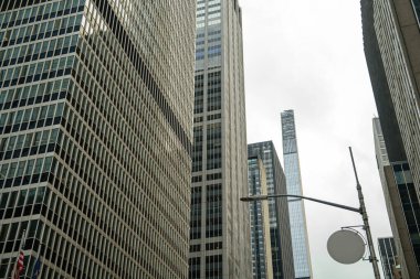 Manhattan, New York 'ta şehir merkezindeki bir sokak lambasının arkasında birkaç modern gökdelen yükseliyor. Şehir sahnesi finans bölgesinin yoğun mimarisini ve dikey ölçeğini vurguluyor.