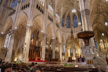 New York City, New York, ABD - 07.31.2024: Resim New York 'taki St. Patricks Katedrali' nin zengin dekore edilmiş kürsüsünü ve altın sunağını gösteriyor. Etrafı boyalı camlarla, kemerlerle, heykellerle ve ziyaretçilerle dolu sıralarla çevrili Gotik.