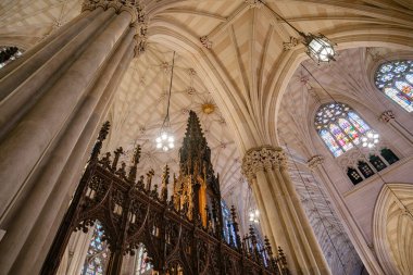 Katedrallerin çarpıcı manzarası. Ayrıntılı sütunlar, vitray pencereler ve süslü ahşap bir yapı. Işık armatürleri ve mimari simetri kutsal mekanın gotik zarafetini vurgular..