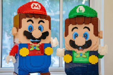 New York City, New York, ABD - 07.31.2024: Mario ve Luigi 'nin renkli tuğlalardan yapılmış büyük LEGO heykellerinin yakın görüntüsü. Şekiller kapalı bir pencerenin önünde sergileniyor..