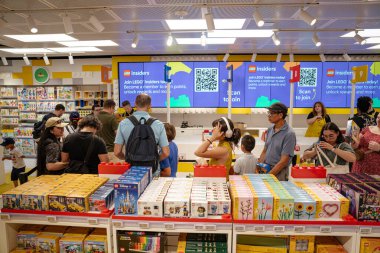 New York, New York, New York, ABD - 07.31.2024: Kalabalık bir LEGO mağazası kasası ailelerle ve renkli setlere bakan müşterilerle doludur. Büyük dijital ekranlar, LEGO İçeridekiler programını tezgahların üzerinde reklam eder.