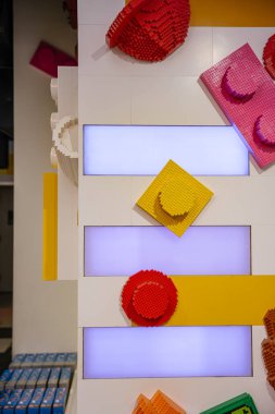 A decorative wall installation features large, colorful plastic bricks arranged in a playful pattern. The background is lit with soft glowing panels, adding a modern and cheerful atmosphere.