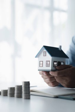 Ev modelleri ve madeni para yığınları olan insanlar, gelir ve mali planlama harcamaları, ev ve gayrimenkul alımları için mali planlama fikirleri hesaplıyor ve kaydediyor..