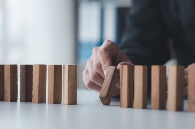 Tahta blokları arka arkaya tutan bir iş adamının yakın plan çekimi, ahşap bloklar iş risk yönetimiyle karşılaştırılır. Risk yönetimi kavramı. Boşluğu kopyala.