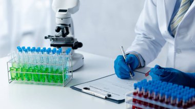 Lab assistant, a medical scientist, a chemistry researcher holds a glass tube through the blood sample, does a chemical experiment and examines a patient's blood sample. Medicine and research concept.