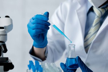 Lab assistant, a medical scientist, a chemistry researcher holds a glass tube through the blood sample, does a chemical experiment and examines a patient's blood sample. Medicine and research concept.