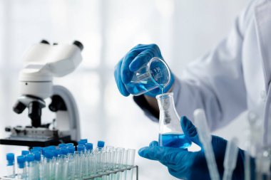 Lab assistant, a medical scientist, a chemistry researcher holds a glass tube through the blood sample, does a chemical experiment and examines a patient's blood sample. Medicine and research concept.