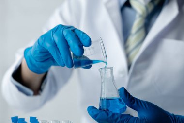 Lab assistant, a medical scientist, a chemistry researcher holds a glass tube through the blood sample, does a chemical experiment and examines a patient's blood sample. Medicine and research concept.