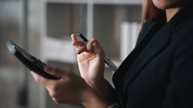 Bir şirketin mali belgelerindeki rakamları hesaplamak için hesap makinesi kullanan bir işadamı, şirketin nasıl büyüyeceğini planlamak için tarihsel finansal verileri analiz ediyor. Mali konsept.