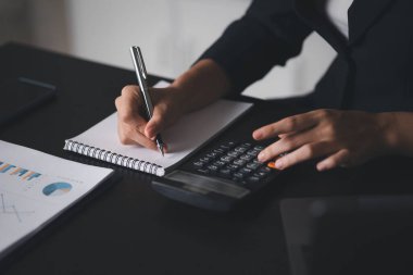 Businessman using a calculator to calculate numbers on a company's financial documents, he is analyzing historical financial data to plan how to grow the company. Financial concept.