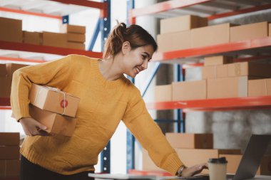 Güzel bir Asyalı işletme sahibi online bir dükkan açıyor, müşterilerin siparişlerini kontrol ediyor, bir kurye şirketi aracılığıyla mal gönderiyor, bir kadının online iş kurma kavramı.
