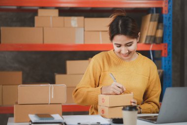 Online store salesperson is writing a customer's shipping address on parcel box before sending it to private carrier for delivery to customer. The idea of opening an online store and packing products.