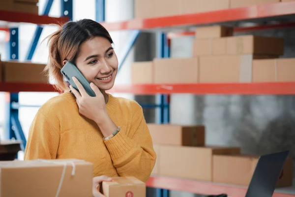 Online store salesperson is talking to customers who place order to confirm their order before packing and shipping with private shipping company. Idea of opening an online store and packing products.