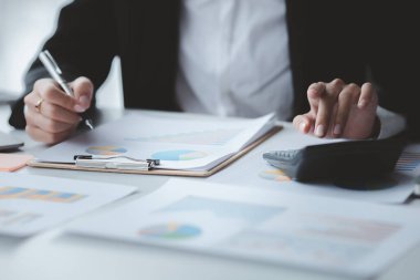 Bir şirketin mali belgelerindeki rakamları hesaplamak için hesap makinesi kullanan bir işadamı, şirketin nasıl büyüyeceğini planlamak için tarihsel finansal verileri analiz ediyor. Finansal konsept. Boşluğu kopyala.