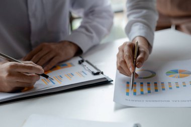 İki işadamı toplantı materyaline işaret ederek, ortak iş sorunlarını geliştirme ve çözme planında birlikte çalıştılar. Büyüme ve kalite için işletme yönetimi kavramı.