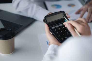 Businessman using a calculator to calculate numbers on a company's financial documents, he is analyzing historical financial data to plan how to grow the company. Financial concept.