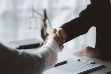 Avukatlar, bu işe ortak yatırım yapan iş ortaklarının zimmetine para geçirme davasında tanıklık etmeye gelen müşterilerle tokalaşıyorlar. Yasal işlemler için avukat tutma kavramı.