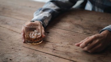 Elinde bir bardak brendi tutan bir adam, bir barda brendi içiyor, alkol içiyor araba kullanma yeteneğine zarar veriyor ve sağlığa zarar verebilir. Alkol konsepti.