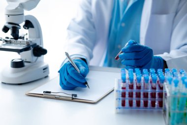 Laboratuvar asistanı, tıp bilimcisi, kimya araştırmacısı kan örneğinde cam bir tüp tutuyor, kimyasal bir deney yapıyor ve hastanın kan örneğini inceliyor. Tıp ve araştırma konsepti.