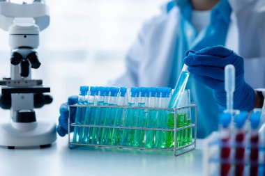 Laboratuvar asistanı, tıp bilimcisi, kimya araştırmacısı kan örneğinde cam bir tüp tutuyor, kimyasal bir deney yapıyor ve hastanın kan örneğini inceliyor. Tıp ve araştırma konsepti.