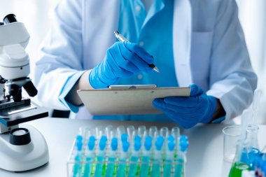 Laboratuvar asistanı, tıp bilimcisi, kimya araştırmacısı kan örneğinde cam bir tüp tutuyor, kimyasal bir deney yapıyor ve hastanın kan örneğini inceliyor. Tıp ve araştırma konsepti.