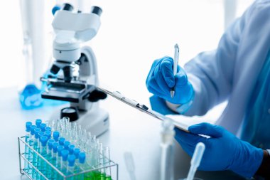 Laboratuvar asistanı, tıp bilimcisi, kimya araştırmacısı kan örneğinde cam bir tüp tutuyor, kimyasal bir deney yapıyor ve hastanın kan örneğini inceliyor. Tıp ve araştırma konsepti.