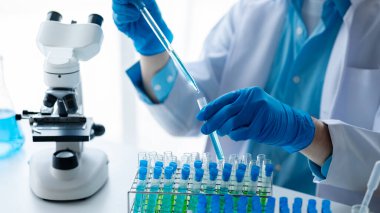 Laboratuvar asistanı, tıp bilimcisi, kimya araştırmacısı kan örneğinde cam bir tüp tutuyor, kimyasal bir deney yapıyor ve hastanın kan örneğini inceliyor. Tıp ve araştırma konsepti.