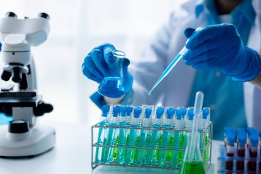 Laboratuvar asistanı, tıp bilimcisi, kimya araştırmacısı kan örneğinde cam bir tüp tutuyor, kimyasal bir deney yapıyor ve hastanın kan örneğini inceliyor. Tıp ve araştırma konsepti.