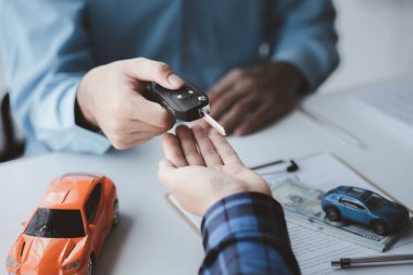 Bir araba kiralama şirketi çalışanı, kiracıyla kira sözleşmesini detaylar ve kiralama şartları hakkında konuştuktan sonra imzalaması gerektiğine işaret etti. Araba kiralama kavramı.