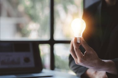 Man hold glowing light bulb, Creative new idea. Innovation, brainstorming, strategizing to make the business grow and be profitable. Concept execution, strategy planning and profit management