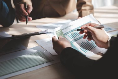 Businessman is reviewing monthly sales documents for analysis and marketing plans for more sales growth, they are the founders of young companies co-founding startups. Sales management concept.