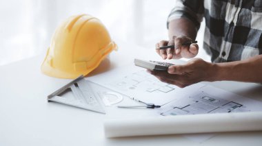 The architect is pointing to the house plans he has designed, he is meeting with engineers and clients to adjust the design before construction starts. Floor plan and interior design concepts.