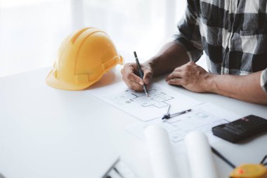 The architect is pointing to the house plans he has designed, he is meeting with engineers and clients to adjust the design before construction starts. Floor plan and interior design concepts.