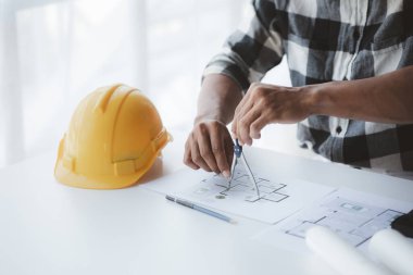 The architect is pointing to the house plans he has designed, he is meeting with engineers and clients to adjust the design before construction starts. Floor plan and interior design concepts.