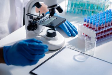 Laboratuvar asistanı, tıp bilimcisi, kimya araştırmacısı kan örneğinde cam bir tüp tutuyor, kimyasal bir deney yapıyor ve hastanın kan örneğini inceliyor. Tıp ve araştırma konsepti.