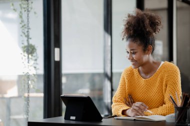 Amerikalı genç bir kadın dizüstü bilgisayarla ofiste oturuyor, evde bilgisayarla online okuyor, üniversite öğrencisi, internet üzerinden eğitim görüyor, internet üzerinden eğitim görüyor..