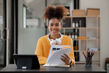 Amerikalı genç bir kadın dizüstü bilgisayarla ofiste oturuyor, evde bilgisayarla online okuyor, üniversite öğrencisi, internet üzerinden eğitim görüyor, internet üzerinden eğitim görüyor..