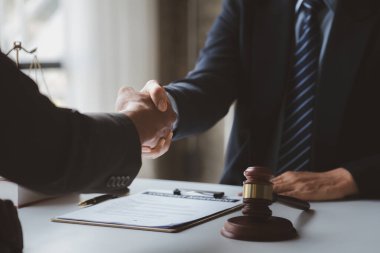 Avukatlar, bu işe ortak yatırım yapan iş ortaklarının zimmetine para geçirme davasında tanıklık etmeye gelen müşterilerle tokalaşıyorlar. Yasal işlemler için avukat tutma kavramı.