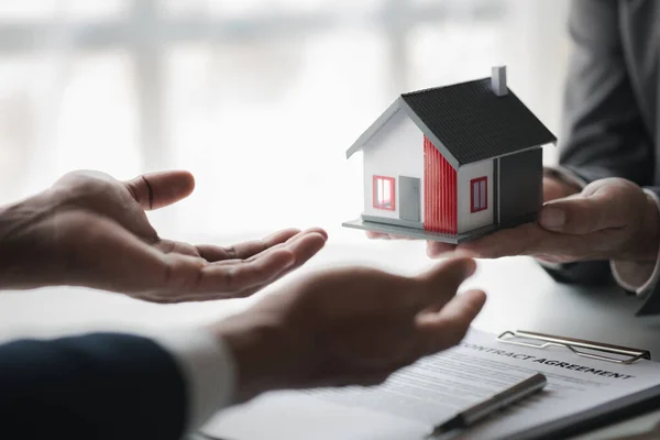 Real estate agents are holding a housing model of the project to be forwarded to customers as home delivery. Real estate trading ideas and bank loans for buying and selling houses and land.