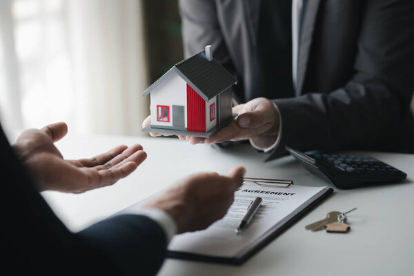 Real estate agents are holding a housing model of the project to be forwarded to customers as home delivery. Real estate trading ideas and bank loans for buying and selling houses and land.