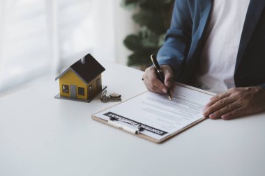 Konut kredisinin satış temsilcisi, sözleşmeye girecek olan müşterinin satış sözleşmesini hazırlıyor ve onaylıyor. Konut ve gayrimenkul satma kavramı.