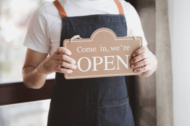 Man holding open/close sign in front of entrance, Goods and Service shop clerk holding sign to notify customers whether the store is open or closed, the opening of the restaurant.